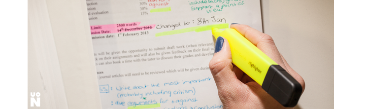 A hand using a luminous yellow highlighter to highlight text - A University of Northampton image